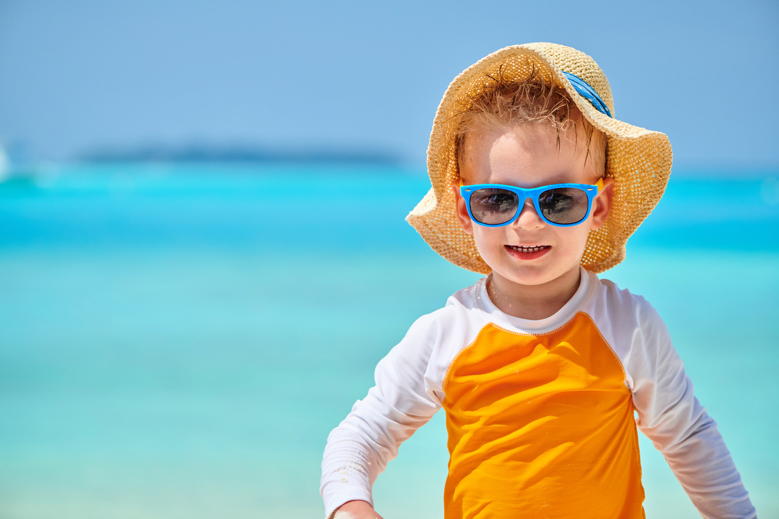 boy wearing rash guard, hat and sunglasses